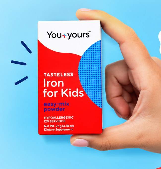 A hand holding a box of Tasteless Iron for Kids