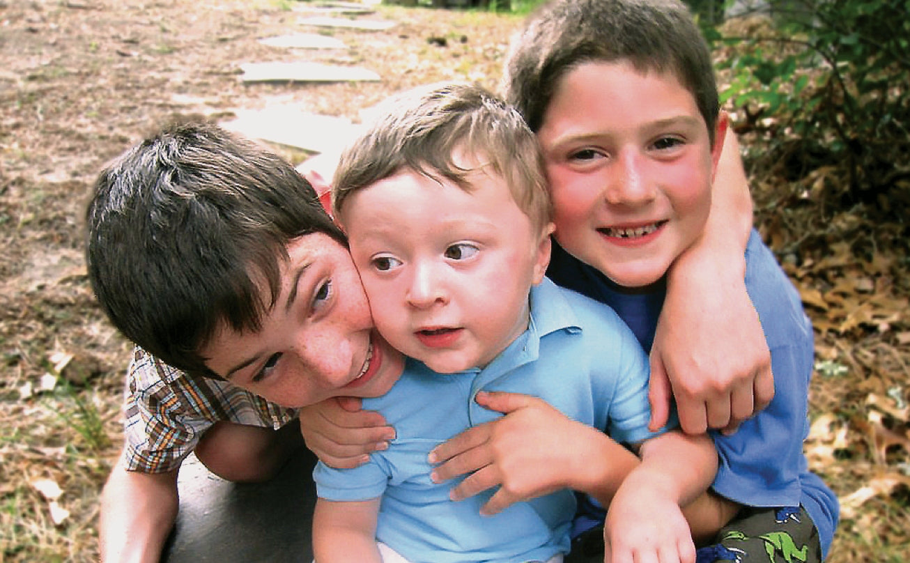 The founder's three sons hugging outdoors